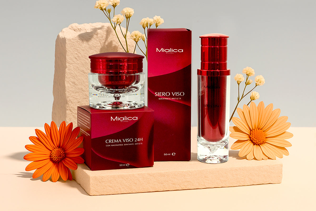 Crema Viso 24H e Siero Viso Mialica con le loro confezioni e dei fiori