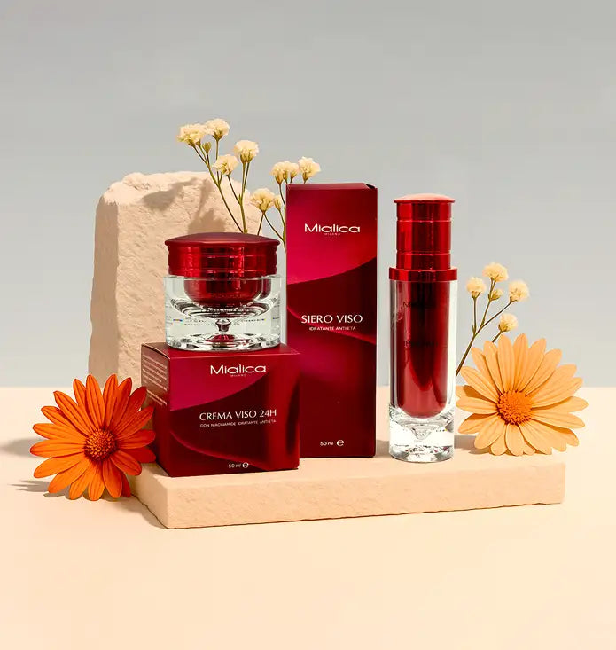 Crema Viso 24H e Siero Viso Mialica tra fiori su supporti in pietra